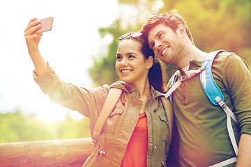 Image showing couple with backpacks taking selfie by smartphone