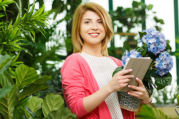Image showing Florist with bouquet holds tablet