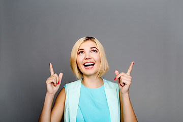 Image showing Smiling blonde showing fingers upstairs