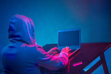 Image showing Hooded computer hacker stealing information with laptop