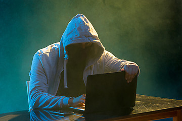 Image showing Hooded computer hacker stealing information with laptop