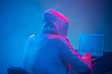 Image showing Hooded computer hacker stealing information with laptop