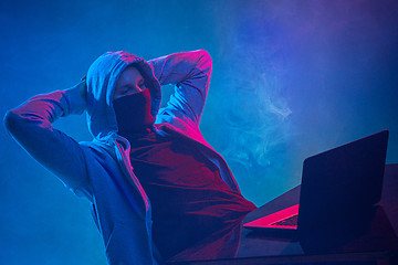 Image showing Hooded computer hacker stealing information with laptop