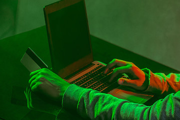 Image showing Hooded computer hacker stealing information with laptop