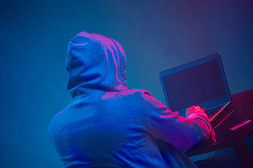 Image showing Hooded computer hacker stealing information with laptop