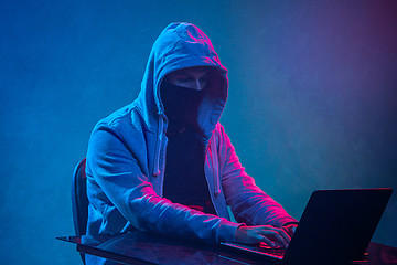 Image showing Hooded computer hacker stealing information with laptop