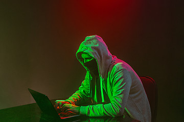 Image showing Hooded computer hacker stealing information with laptop