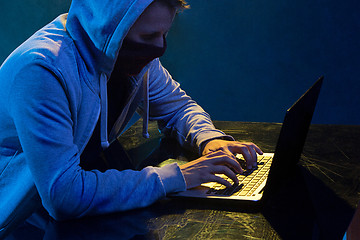 Image showing Hooded computer hacker stealing information with laptop