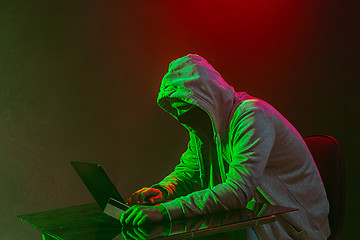 Image showing Hooded computer hacker stealing information with laptop