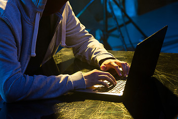 Image showing Hooded computer hacker stealing information with laptop