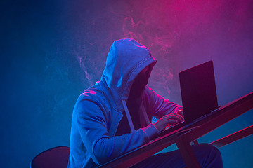 Image showing Hooded computer hacker stealing information with laptop