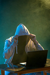 Image showing Hooded computer hacker stealing information with laptop