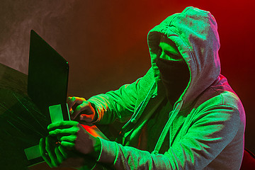 Image showing Hooded computer hacker stealing information with laptop