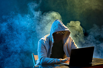 Image showing Hooded computer hacker stealing information with laptop