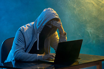 Image showing Hooded computer hacker stealing information with laptop