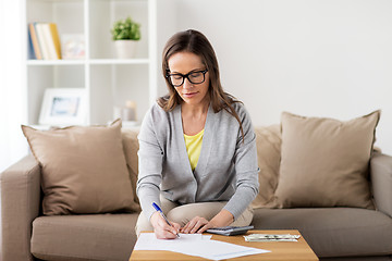 Image showing woman with money, papers and calculator at home