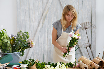 Image showing Young blond florist makes bouquet