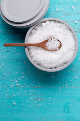 Image showing Sea salt in an stone bowl with small wooden spoon on a blue wooden table