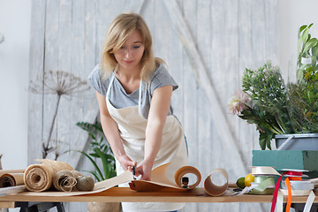 Image showing Blonde florist cuts wrapping paper