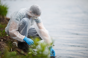 Image showing Ecologist takes sample of water