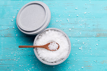 Image showing Sea salt in an stone bowl with small wooden spoon on a blue wooden table