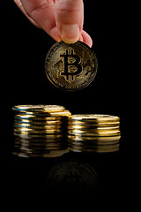 Image showing hand pouring bitcoin from row on black background, conceptual