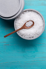 Image showing Sea salt in an stone bowl with small wooden spoon on a blue wooden table