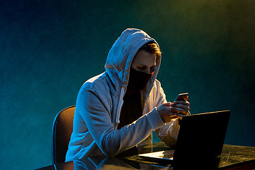 Image showing Hooded computer hacker stealing information with laptop