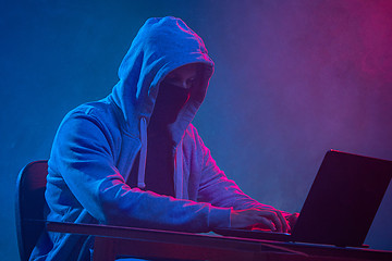 Image showing Hooded computer hacker stealing information with laptop