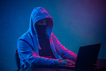 Image showing Hooded computer hacker stealing information with laptop