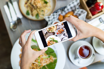 Image showing Woman taking photo on cellphone on dish