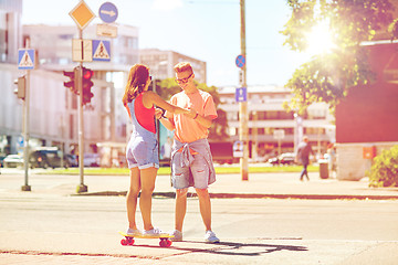 Image showing teenage couple riding skateboards on city street