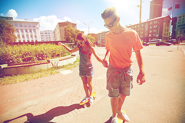 Image showing teenage couple riding skateboards on city street