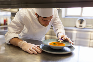 Image showing male chef decorating dish with pansy flower