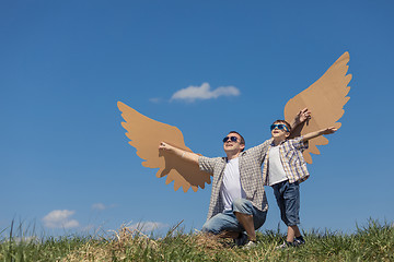 Image showing Father and son playing with cardboard toy wings in the park at t