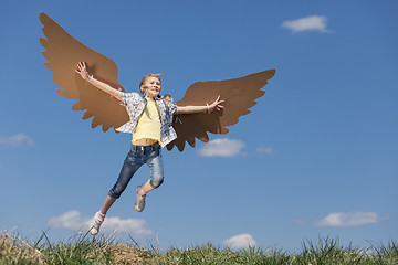 Image showing Little girl playing with cardboard toy wings in the park at the 