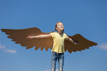 Image showing Little girl playing with cardboard toy wings in the park at the 