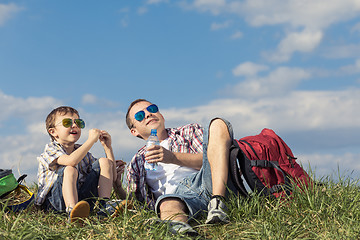 Image showing Father and son sitting in the field at the day time.