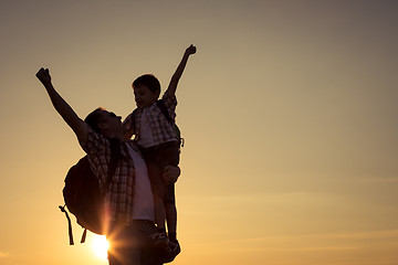 Image showing Father and son walking on the field at the sunset time.