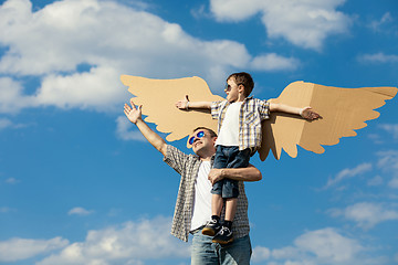 Image showing Father and son playing with cardboard toy wings in the park at t