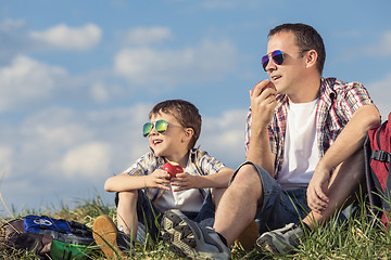 Image showing Father and son sitting in the field at the day time.