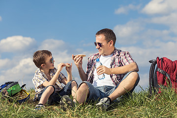 Image showing Father and son sitting in the field at the day time.