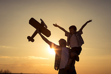 Image showing Father and son playing with cardboard toy airplane in the park a