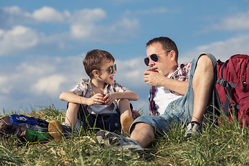 Image showing Father and son sitting in the field at the day time.