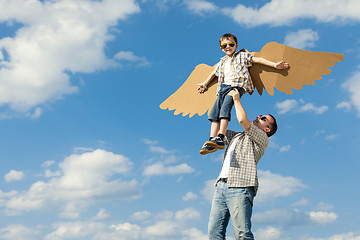 Image showing Father and son playing with cardboard toy wings in the park at t