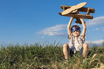 Image showing Little boy playing with cardboard toy airplane in the park at th