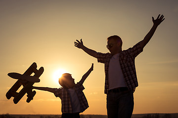 Image showing Father and son playing with cardboard toy airplane in the park a