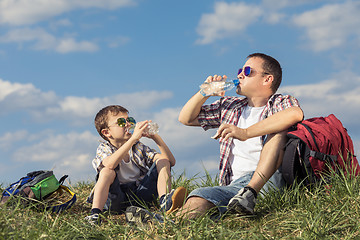 Image showing Father and son sitting in the field at the day time.