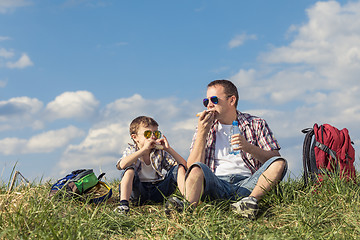 Image showing Father and son sitting in the field at the day time.