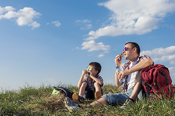 Image showing Father and son sitting in the field at the day time.